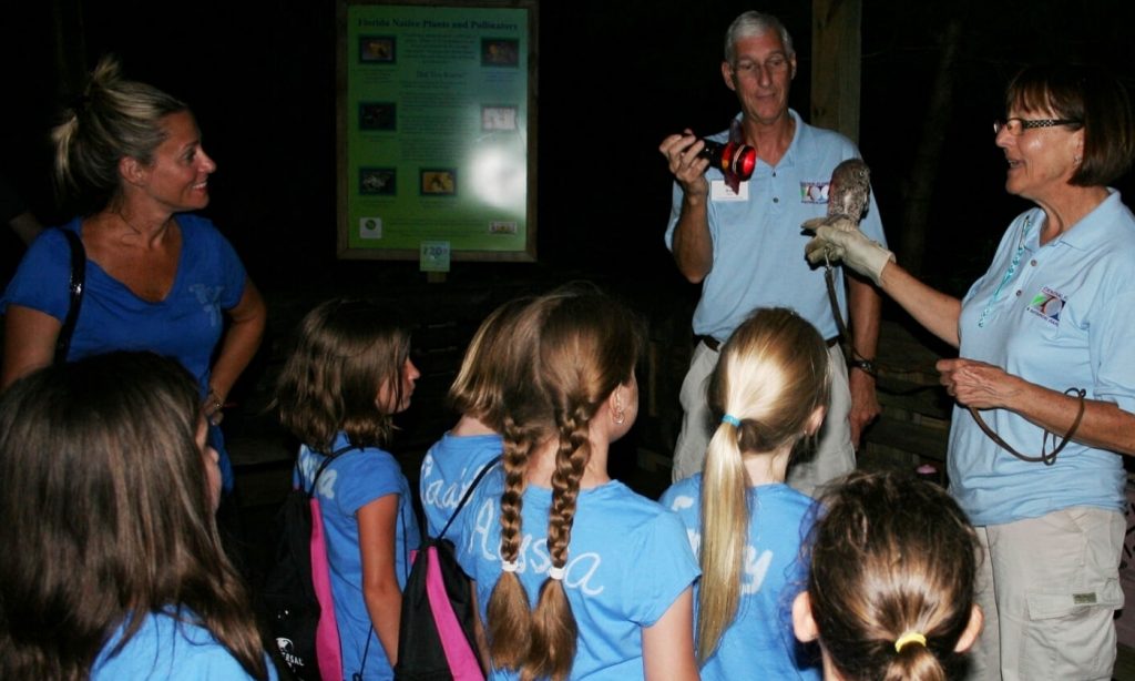 Two guides explaining to some children about a bird